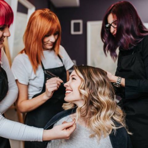 Two stylists finishing a client's blonde balayage