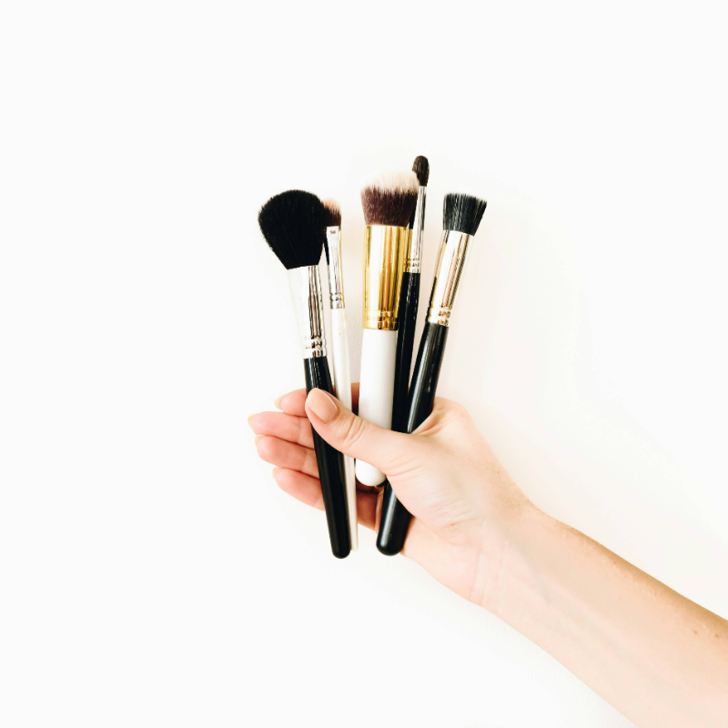 Hand holding a set of professional makeup brushes
